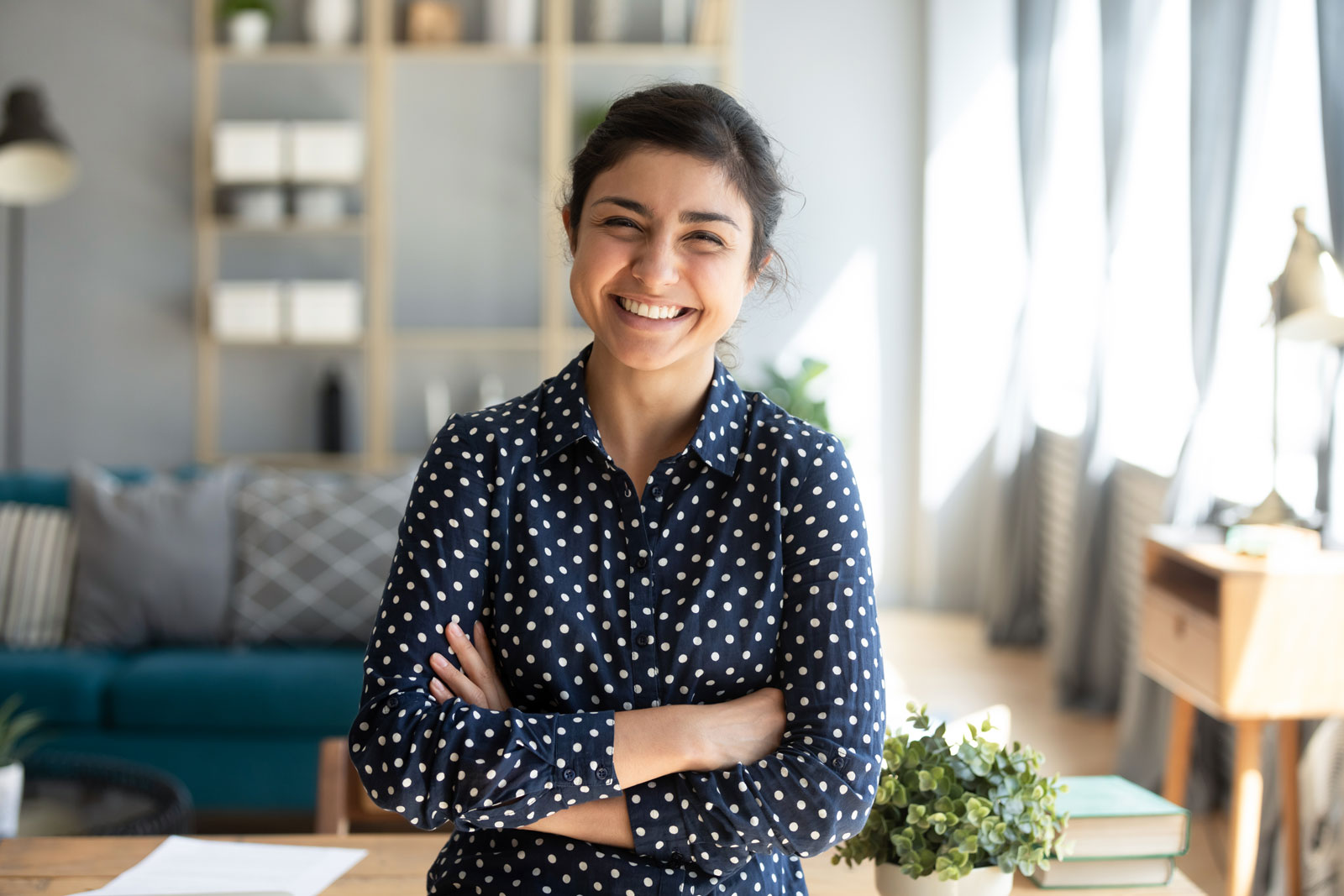 Smiling pretty young adult indian woman looking at camera posing at modern home arms crossed, cheerful happy ethnic girl student self employed lady laughing enjoying distance job education, portrait